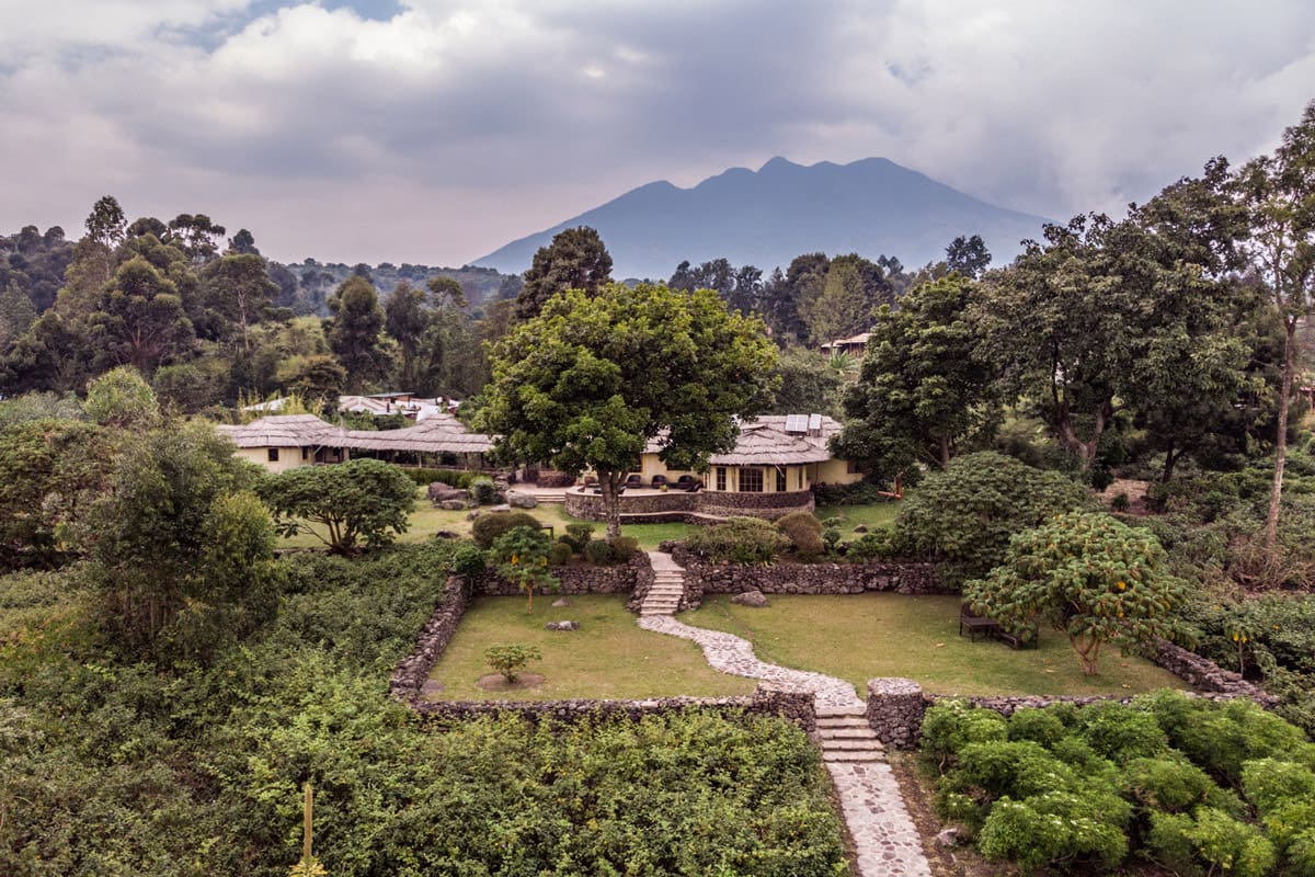 Aerial view of Mount Gahinga Lodge with lush greenery and the Virunga Volcanoes in the background, showcasing the serene and luxurious setting of the lodge in Uganda.