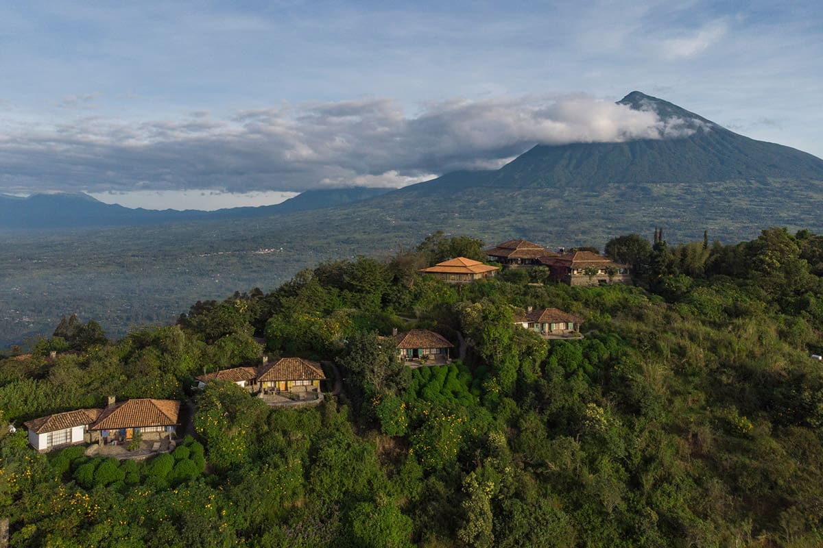 Aerial view of Virunga Lodge with lush greenery and the Virunga Volcanoes in the background in Rwanda.