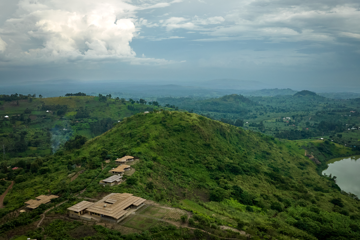 Aerial view of Kibale Lodge in Uganda, situated on a lush green hillside overlooking Lake Lugembe, showcasing the lodge's stunning natural setting and safari experience.